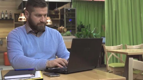 Focused man working, writing on laptop computer, in pub, cafe, steadycam Video stock 73068674