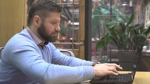 Focused man working, writing on laptop computer, in pub, profile, steadicam shot 库存影片 73073015