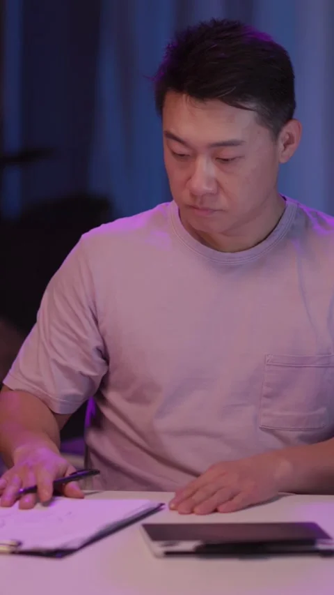 A focused man works at a cozy table, using a laptop and tablet Stock Footage 313788773