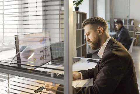 Focused manager reviewing analytics on computer in open plan contemporary office Stock Photos