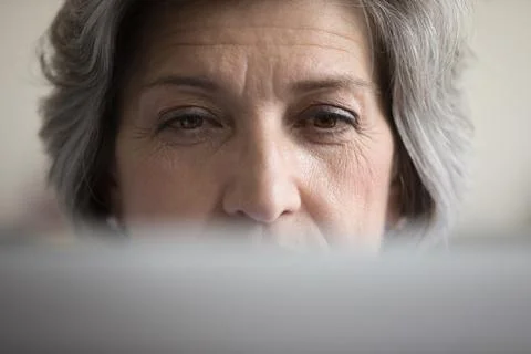 Focused mature grey haired computer user woman looking at laptop Stock Photos