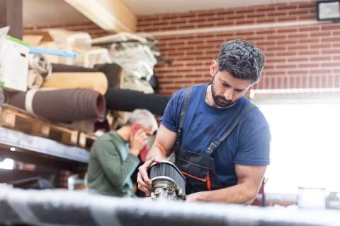Focused mechanic with car engine part in auto repair shop Stock Photos