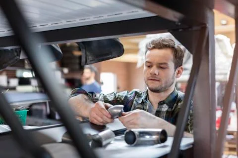 Focused mechanic examining car part in auto repair shop Stock Photos