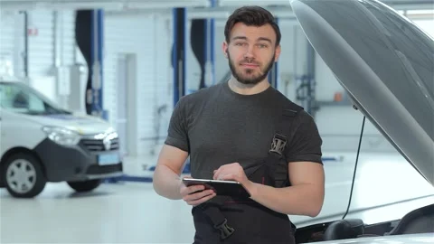Focused mechanic using a tablet to diagnose a vehicle at the car service Stock Footage 311673417