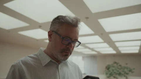 Focused Mid-Aged Businessman Using Mobile Phone in Modern Office Stock Footage 308616574