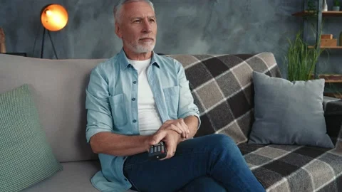Focused middle aged man sit divan intrigued watch interesting film in room Stock Footage 166624442