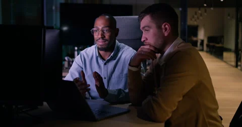 Focused multicultural team collaborating late at night, analyzing data and Stock Footage 305594010
