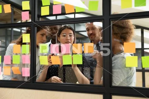 Focused multiethnic business team brainstorm with sticky notes in office Stock Photos
