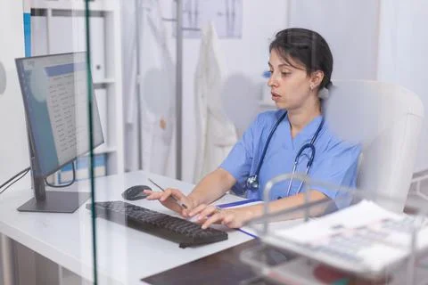 Focused nurse in blue coat checking appointments using computer Stock Photos