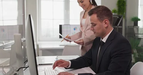 Focused office worker analyzing finance data on desktop computer with colleague Stock Footage 327955408