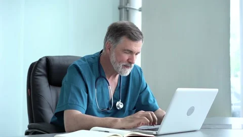 Focused old doctor physician using laptop at office desk. Stock Footage 135186094