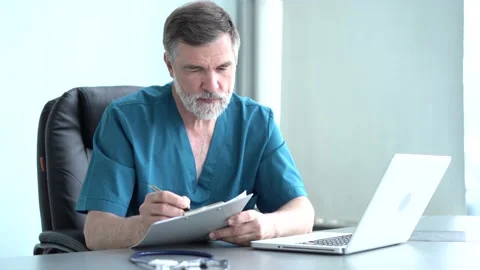 Focused old doctor physician using laptop at office desk. Stock Footage 135186102