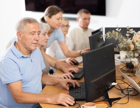 Focused older gentleman using computer at internet cafe Fotos de archivo