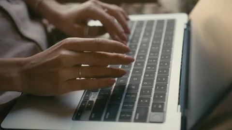 A Focused Pair of Hands Swiftly Typing on a Laptop While Seated Outdoors in Stock Footage 280848526