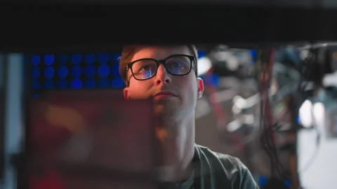 Focused person in glasses working at computer with bright studio lights in Vídeo Stock 317538628
