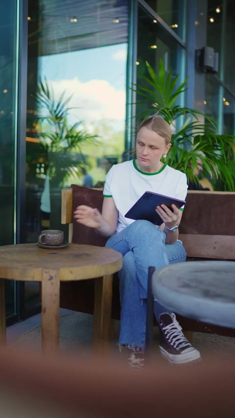 Focused Person Using Tablet in a Modern Cafe Stock Footage 335457118