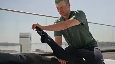 Focused physiotherapist attentively adjusting ankle support for injury recovery Stock Footage 274192582