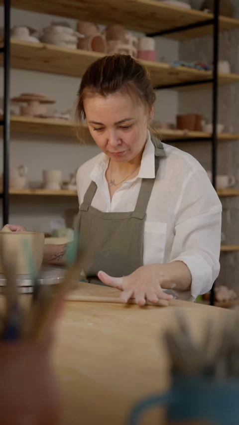 Focused potter refining a clay pot on the wheel, immersed in the detailed Stock Footage 266674369