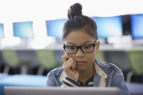 Focused pre-adolescent girl using laptop in classroom Foto stock