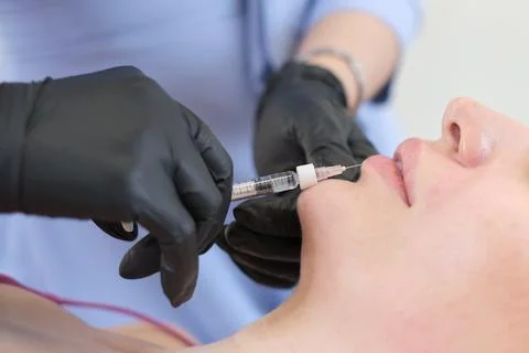 Focused on precision, a lip augmentation takes place. Reflecting society's Stock Photos