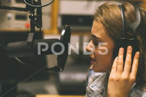 Focused pretty singer recording a song Stock Photos