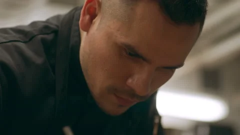 Focused professional chef garnashing a dish for serving in industrial kitchen wi Stock Footage 199459305