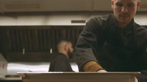 Focused professional chef removing plastic wrap from tray in industrial kitchen Video stock 199460610