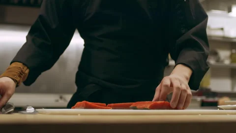 Focused professional chef taking fillets of salmon and cutting them into serving Video stock 199460002