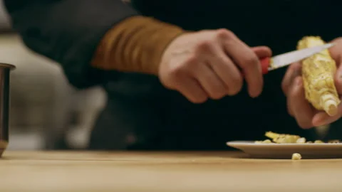 Focused professional chef using a pairing knife to cut corn kernels off the cob Stock Footage 199457276