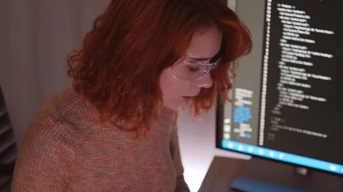 Focused professional in protective glasses codes at desktop monitor in dim Stock Footage 318578713