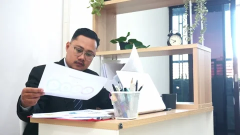 Focused professional reviewing financial documents and analyzing reports at desk Stock Footage 327290319