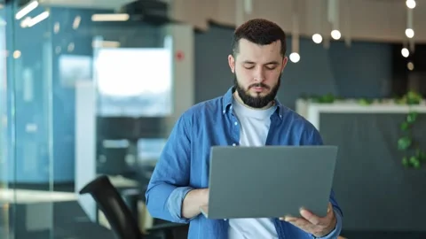 Focused Professional Working on Laptop in Modern Office Environment Stock Footage 329276537