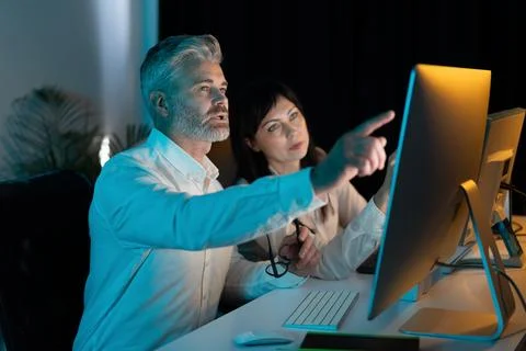 Focused Professionals Collaborating on Computer Project Late at Night Stock Photos