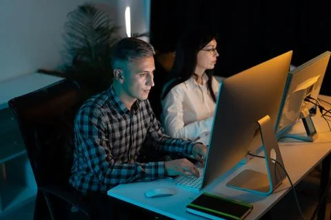 Focused Professionals Working Late on Computers in an Office Stock Photos