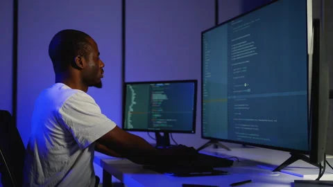 Focused programmer coding on multiple screens at night Stock Footage 305009100
