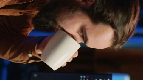 Focused programmer drinking coffee in apartment while solving database errors Stock Footage 265108120