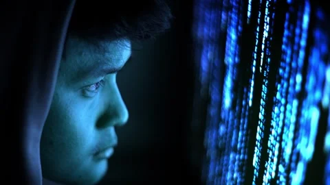 Focused programmer in hoodie looking at blue binary code on monitor Stock Footage 336187923