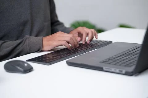Focused programmer typing on a laptop in a workspace environment conducive to Stock Photos