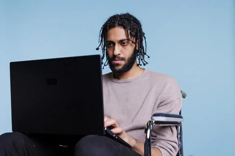 Focused programmer in wheelchair developing software on laptop 스톡 사진