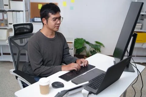 Focused Programmer Working on Computer in Tech Workspace with Multiple Screen Stock Photos