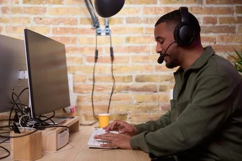 Focused programmer working on computer wearing headset in modern office 写真素材