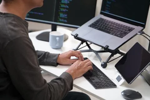 Focused Programmer Working at a Home Office Setup with Multiple Monitors and Foto stock