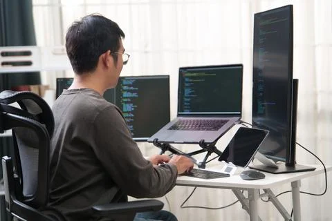 Focused Programmer Working with Multiple Monitors in an Office Environment fo Stock Photos