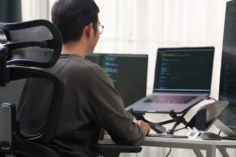 Focused Programmer Working on Multiple Monitors in a Productive Workspace Stock Photos