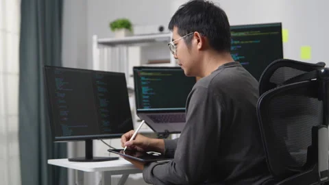 Focused Programmer Working Remotely on Multiple Monitors with Programming C.. 動画素材 336680367