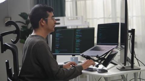 Focused Programmer Working Remotely with Multiple Monitors and a Laptop Setup Stock-Footage 336680574