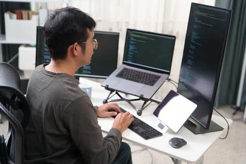 Focused Programmer Working on Software Development at Multiple Computer Scree 写真素材