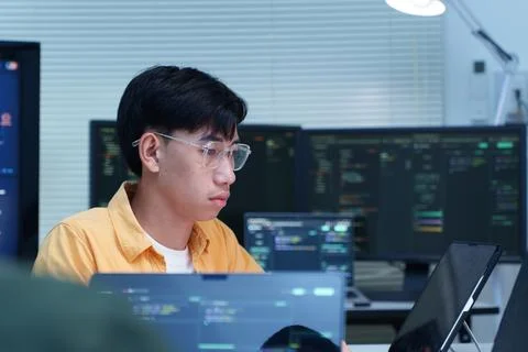 Focused Programmer Writing Code on Multiple Screens Stockfoto's