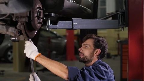 Focused repairman using tool to check car chassis Stock Footage 123507340