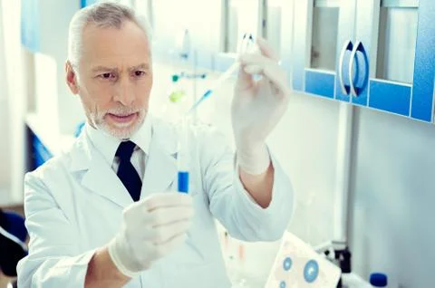 Focused researcher using pipette while working with chemical liquids Foto stock